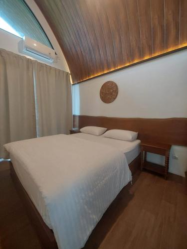 a bedroom with a white bed with a wooden ceiling at Villa Saung Wira in Cirebon