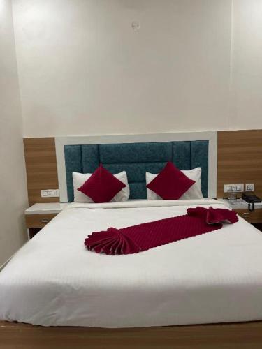 a bedroom with a large white bed with red pillows at Hotel Apple Rose Near Harish Dhaba in Chandīgarh