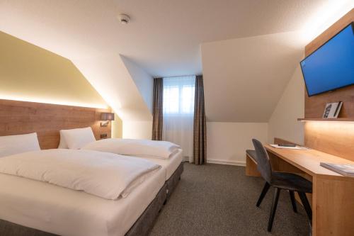 a hotel room with two beds and a desk at Romantik Hotel & Restaurant Sternen in Kriegstetten
