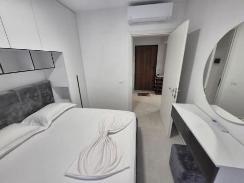 a bedroom with a white bed and a mirror at New Comfort Apartment in Golem