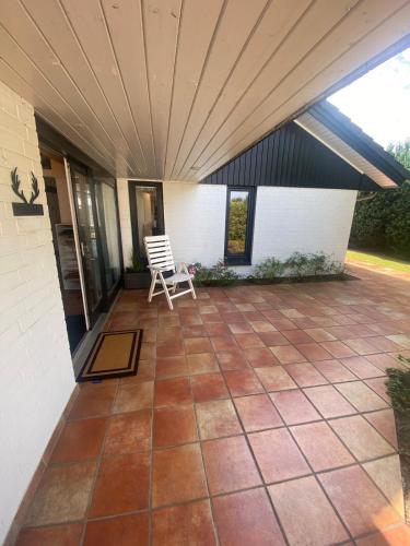 a patio with a white chair on a house at Direkt am See mit privatem Sandstrand in Güster