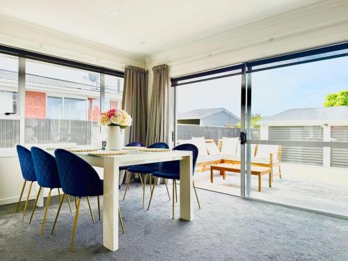 a dining room with a white table and blue chairs at 6 Guests Family Home 7 Minutes to Airport in Christchurch