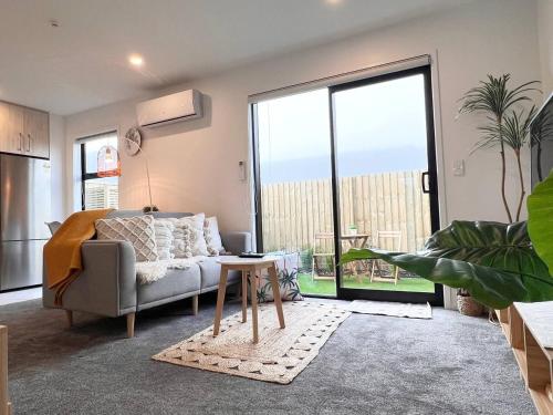 a living room with a couch and a table at Cozy Rattan Escape Winter Warmth in Central CHC in Christchurch