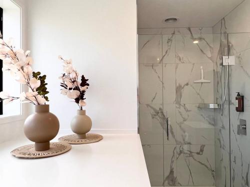 two vases on a counter in a bathroom with a shower at New 3 Storey luxe townhouse on quiet street in Christchurch
