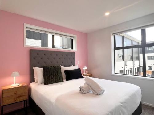 a bedroom with a large white bed with pink walls at New 3 Storey luxe townhouse on quiet street in Christchurch