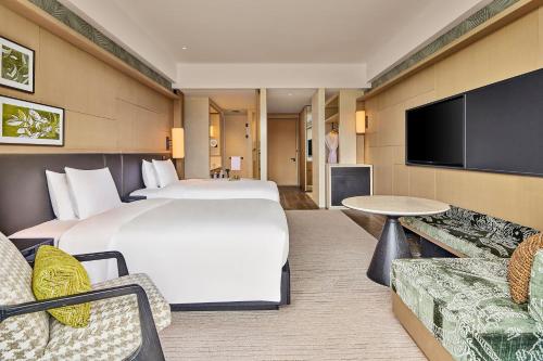 a hotel room with two beds and a flat screen tv at Shu Hua Hotel Tianmu Mountain, Curio Collection By Hilton in Hangzhou