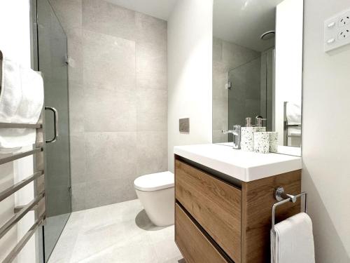 a bathroom with a toilet and a sink and a mirror at Lux Achi-Design Townhouse park view in Latimer Sq in Christchurch
