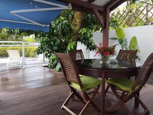 a table and chairs on a deck with a tree at F2 pour une pause hors du temps in Ducos