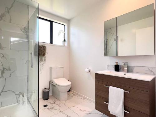 a bathroom with a toilet and a glass shower at Awesome new townhouse with KING Bed on Armagh in Christchurch