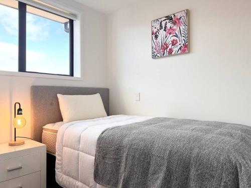 una camera da letto bianca con un letto e una finestra di Spacious luxe 3 story townhouse on Cashel street a Christchurch