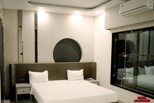 Un dormitorio con una cama blanca y un espejo. en Hotel Adhishree, en Sehore