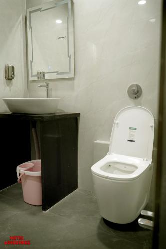 Un baño con un inodoro blanco y un lavabo. en Hotel Adhishree, en Sehore