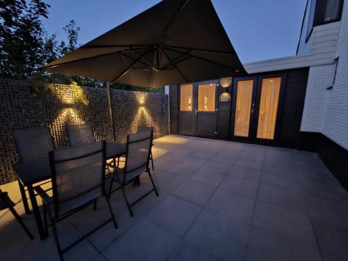 a patio with a table and chairs and an umbrella at Leaf & Lounge Twente in Oldenzaal