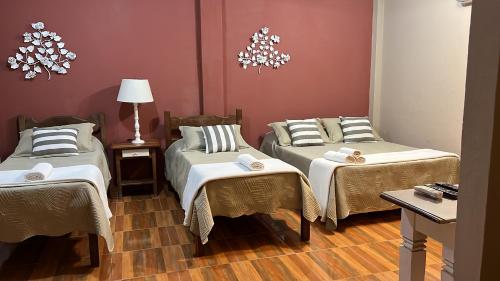 a room with two beds and a table and a lamp at CASA POR do SOL in Tiradentes