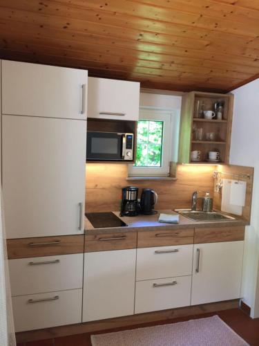 a kitchen with white cabinets and a microwave at Appartements im Park in Krumpendorf am Wörthersee