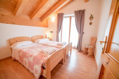 Un dormitorio con dos camas y una ventana en Residence Alpenrose, en Molveno