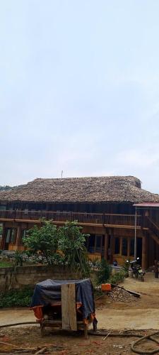 a building with a roof with a table in front of it at Homestay Mộc Bản in Hữu Lũng