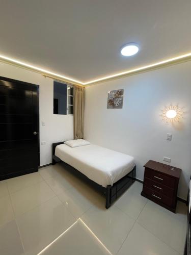 a small bedroom with a bed and a night stand at Hostal Balcon del Cielo in Baños