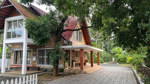 a house with a white fence in front of it at Cottage on Riverside in Irinjālakuda