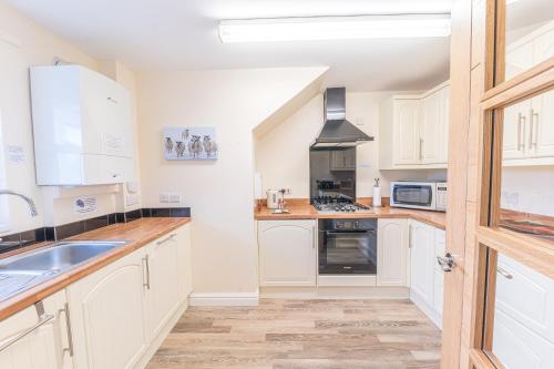 a kitchen with white cabinets and a sink at Tiggs Place, 5 Howrahs Court in Keswick