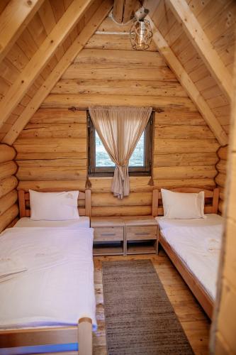 a bedroom with two beds in a log cabin at Etno selo Pivska Vila in Nedajno