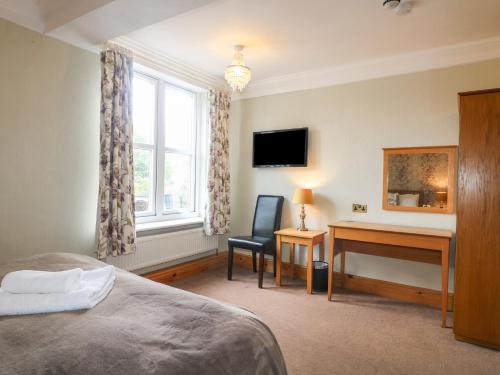 a bedroom with a bed and a desk and a window at Hambleton House in Derby