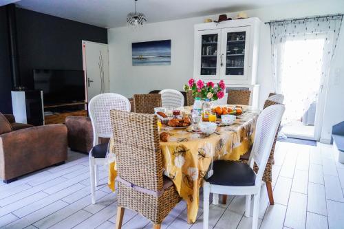 a dining room with a table with food and flowers on it at Les Bleuets - Erdivines in Erdeven