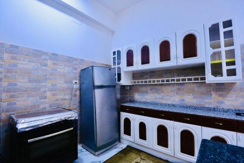 a kitchen with a refrigerator and a brick wall at SunWing guest house in Luxor