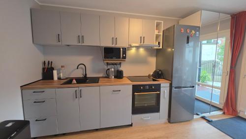 a kitchen with white cabinets and a stainless steel refrigerator at Alpine Yard Nest Busteni in Buşteni