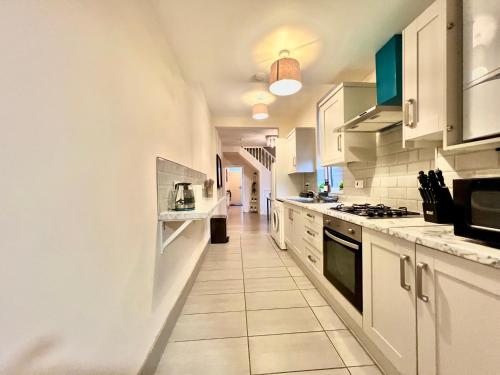 a kitchen with white cabinets and a tile floor at Perfect for Work Trips & Families, Spacious 2BR, WiFi, Free Parking, Sleeps 5 in Spon End