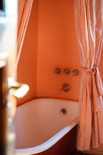 an orange bathroom with a tub and a shower curtain at La Negrita Casa de Campo in Azcuénaga