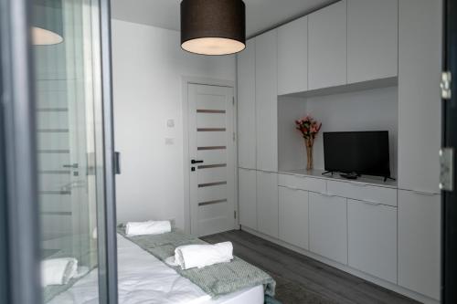 a bathroom with white walls and a tv and a mirror at Elegance Rezidence in Arad