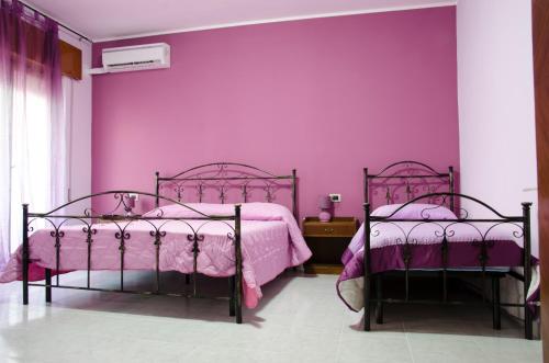 two beds in a room with purple walls at Sicily House in Mazara del Vallo