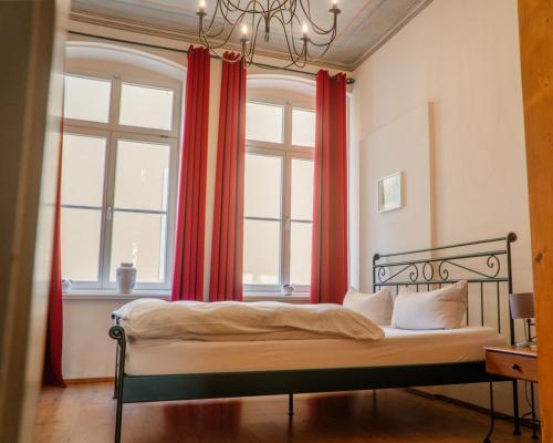 a bedroom with a bed in front of a window with red curtains at Albergo-Toscana in Bad Schandau