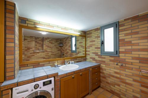 a bathroom with a sink and a washing machine at MiraFysee Farm in Argolikón