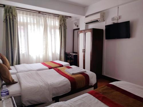 a hotel room with two beds and a window at Hotel Pleasure Home in Kathmandu