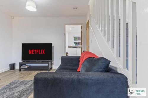 a living room with a blue couch and a tv at Lisa's House in Leek