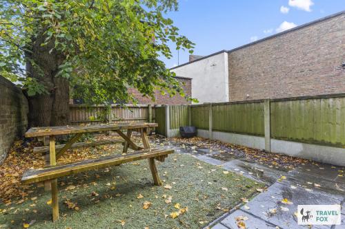 a wooden picnic table sitting next to a fence at Lisa's House in Leek