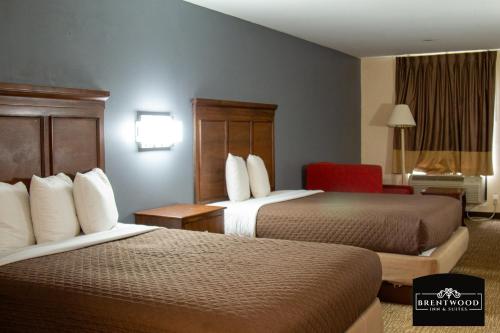 a hotel room with two beds and a red chair at BrentwoodInn&suites in Richmond