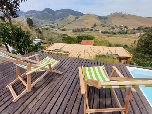 two chairs sitting on a deck next to a pool at Fraga da Mantiqueira in São Bento do Sapucaí