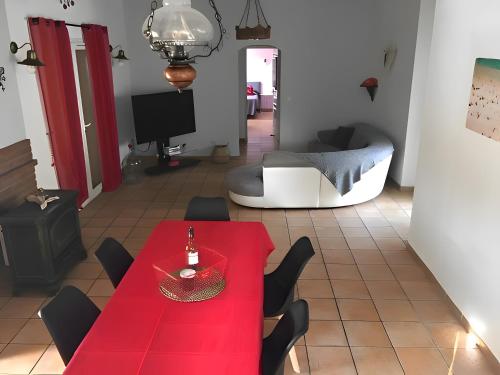ein Wohnzimmer mit einem roten Tisch und Stühlen in der Unterkunft Gîte Du Midi - La Noria in Cazouls-lès-Béziers