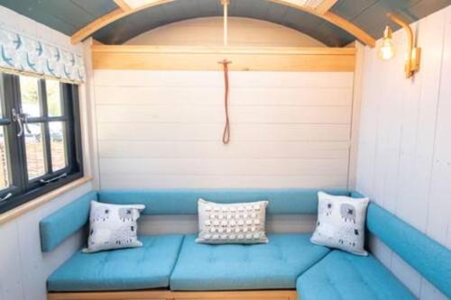 a blue bench in a room with pillows at BaaNone Shepherds Hut in Wimborne Minster
