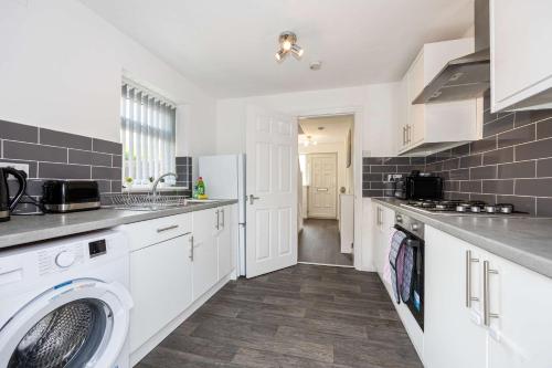 a kitchen with white cabinets and a washer and dryer at Bright and Modern 2 Bed Home w Garden in Liverpool in Liverpool