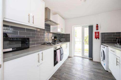 a kitchen with white cabinets and a stove top oven at Bright and Modern 2 Bed Home w Garden in Liverpool in Liverpool