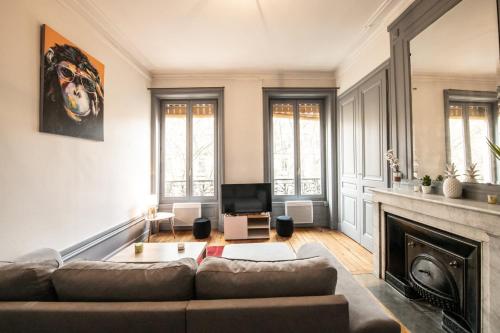Una sala de estar con un sofá y una chimenea. en Appartement de charme dans le 6e - central, en Gare des Brotteaux