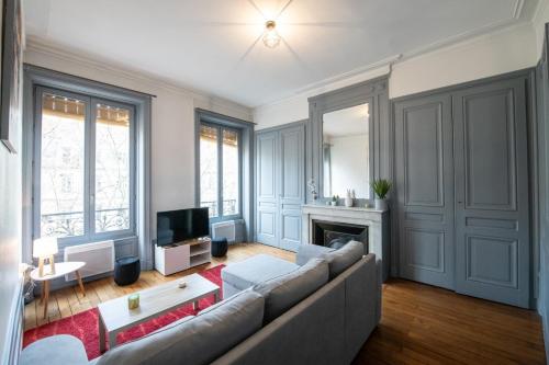 Una sala de estar con un sofá y un televisor. en Appartement de charme dans le 6e - central, en Gare des Brotteaux