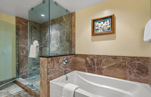 a bathroom with a tub and a glass shower at Honua Kai Resort And Spa By Maui Resort Rentals in Lahaina