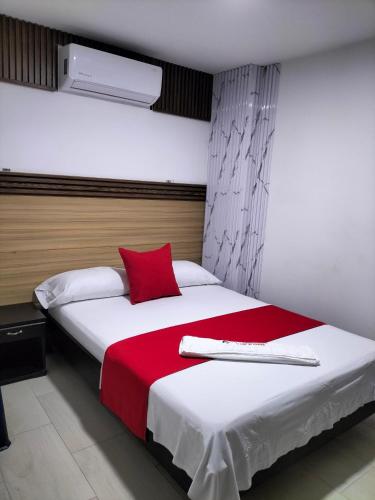 a bedroom with a large bed with a red pillow at Hotel plaza centro in Florencia
