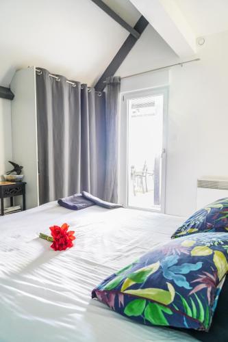 a white bed with a red flower on it at Les Bleuets - Erdivines in Erdeven