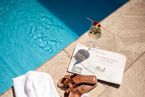 a pair of sandals and a book next to a swimming pool at Egger Apartments & Suites in Villandro